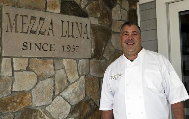 Chef and third-generation owner E.J. Cubellis beside the Mezza Luna Since 1937 stone sign